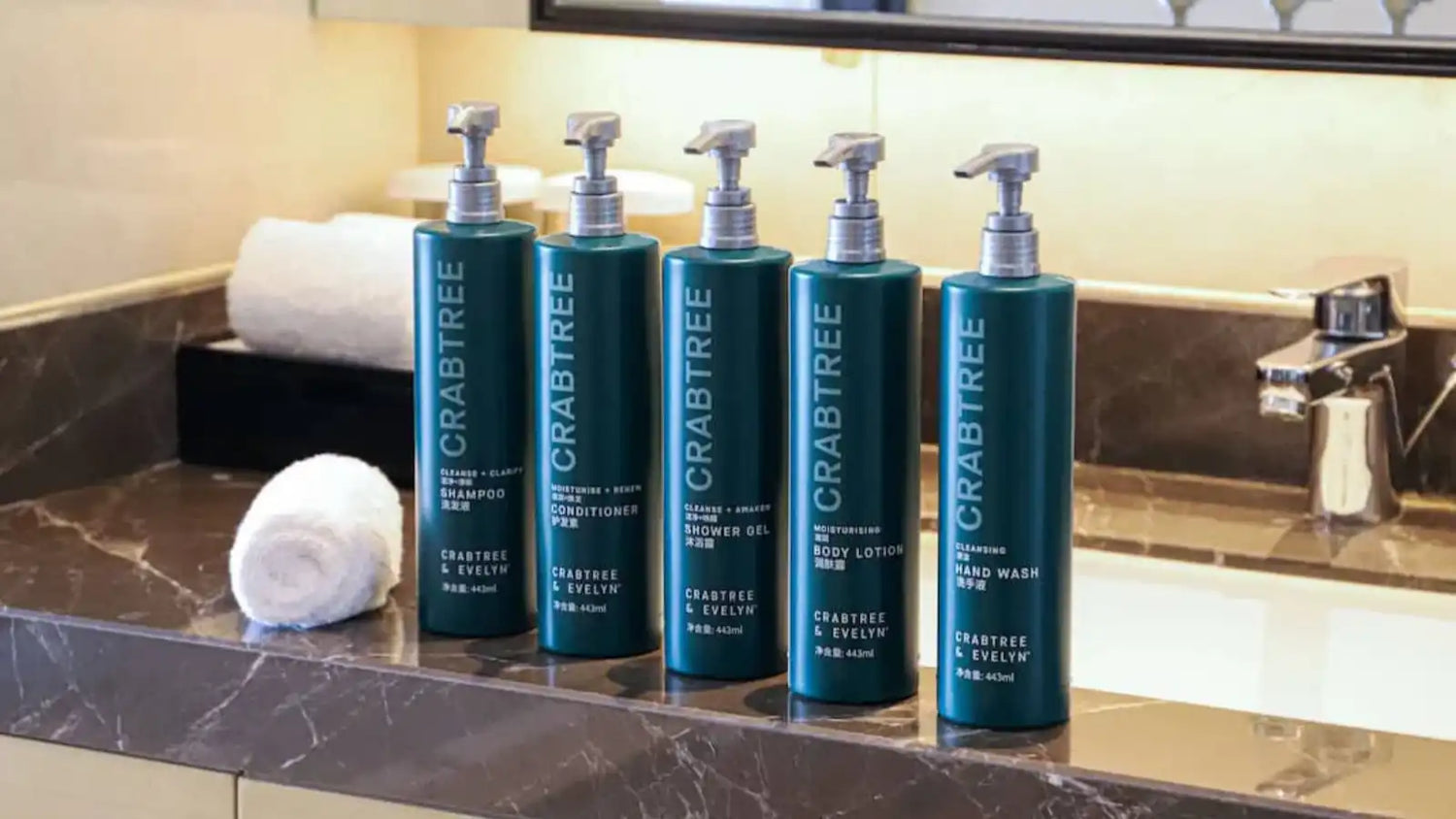 The Crabtree &amp; Evelyn 5-piece toiletries set displayed on the sink includes shampoo, conditioner, body lotion, shower gel, and hand soap.